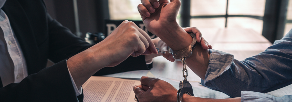 Person with handcuffs being interviewed in interrogation room