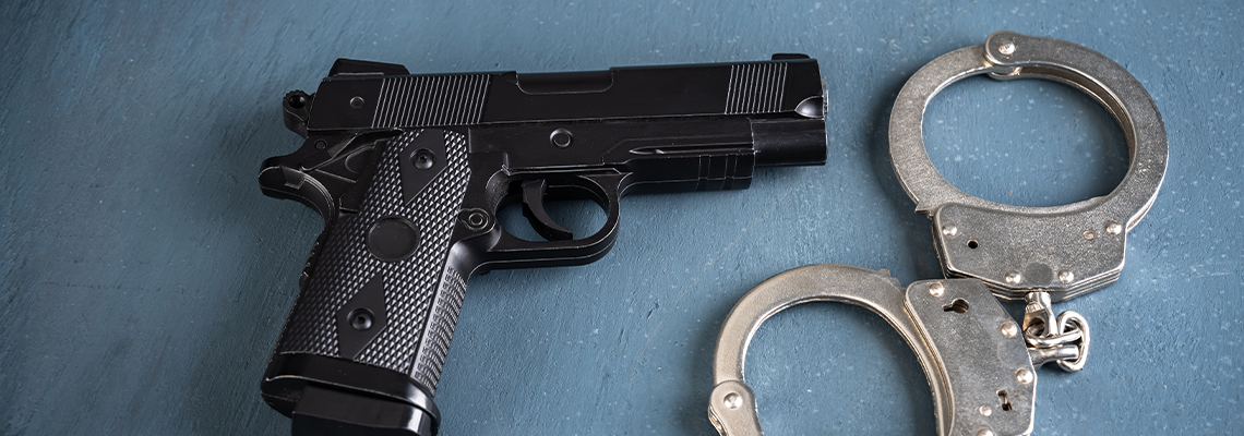 Gun and handcuffs on blue background
