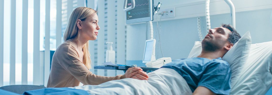 Worrying Wife sits beside injured husband in hospital bed