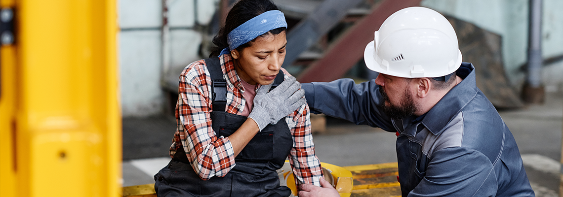Man in construction hat giving first aid to woman