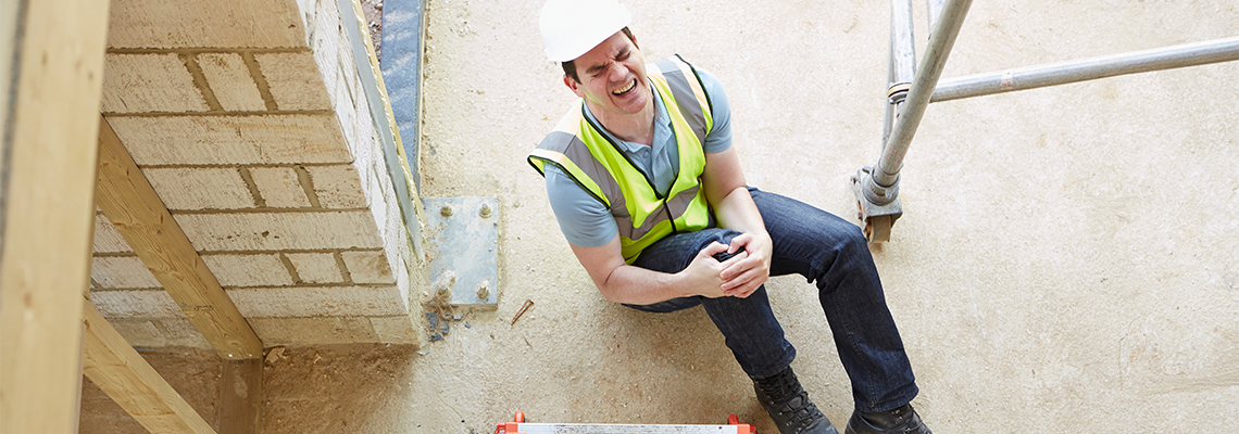 Construction Worker on ground holding his knee after falling at work