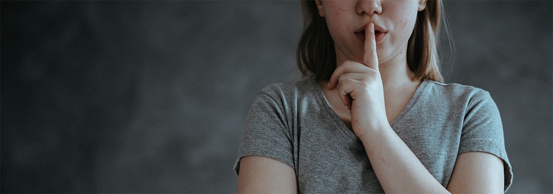 Person doing shushing motion with finger in front of lips