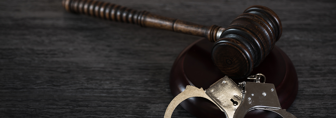Handcuffs and Gavel on Dark Rustic Table