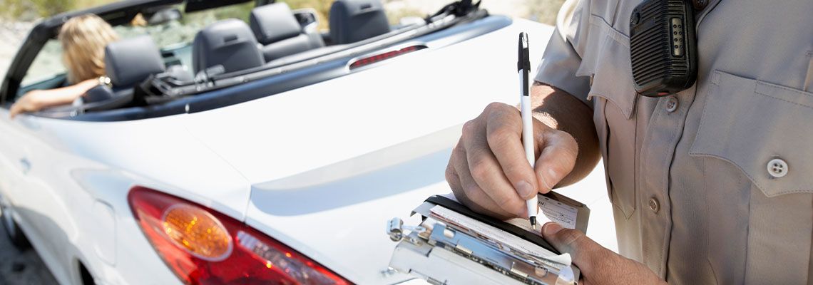 Closeup of a cropped police officer writing traffic ticket