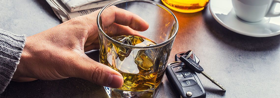 Glass of alcohol in hand and keys to the car