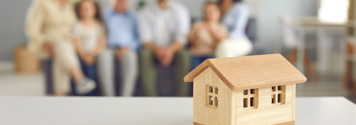 Closeup of small little toy house on table against blurred background of living-room