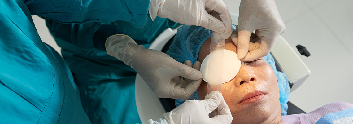 Crop shot from above of careful surgeons applying patch with tape on eye