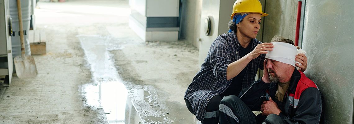 Co-Worker bandaging injured head of a factory worker