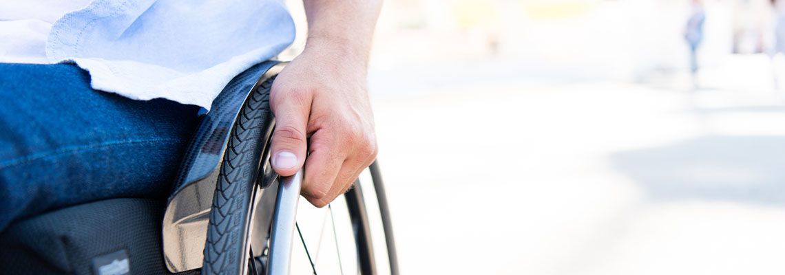 Hand of man in wheel of a wheelchair