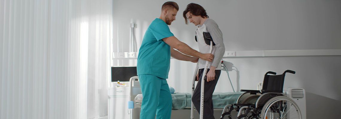 Doctor helping young man to walk in crutches