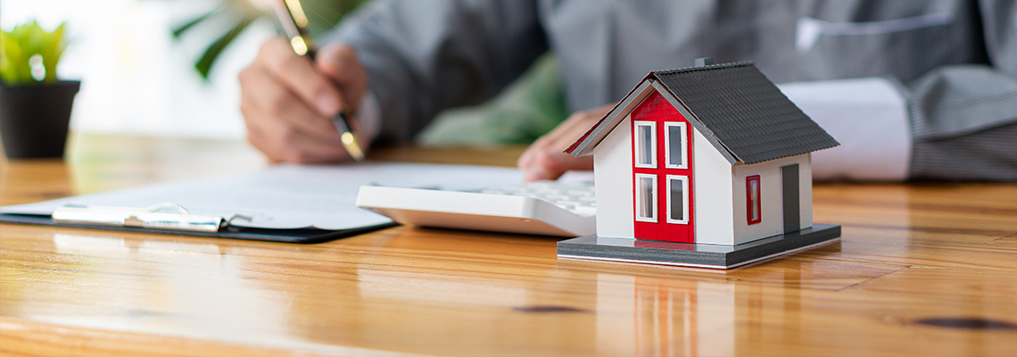 Businessmen holding pens, signing home titles with insurance.