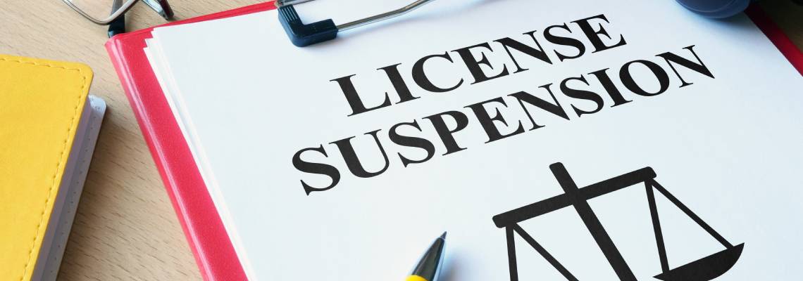 License suspension word on notepad with scale of justice figure
