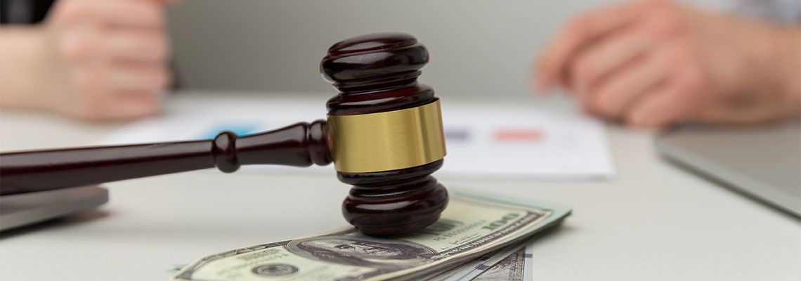 Gavel on dollar bills and divorced couples in background
