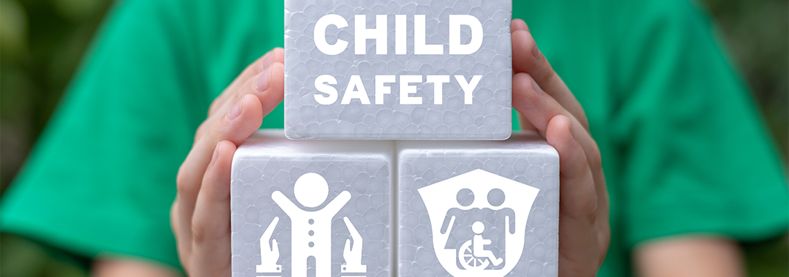 Little girl holding white plastic foam blocks with inscription: CHILD SAFETY
