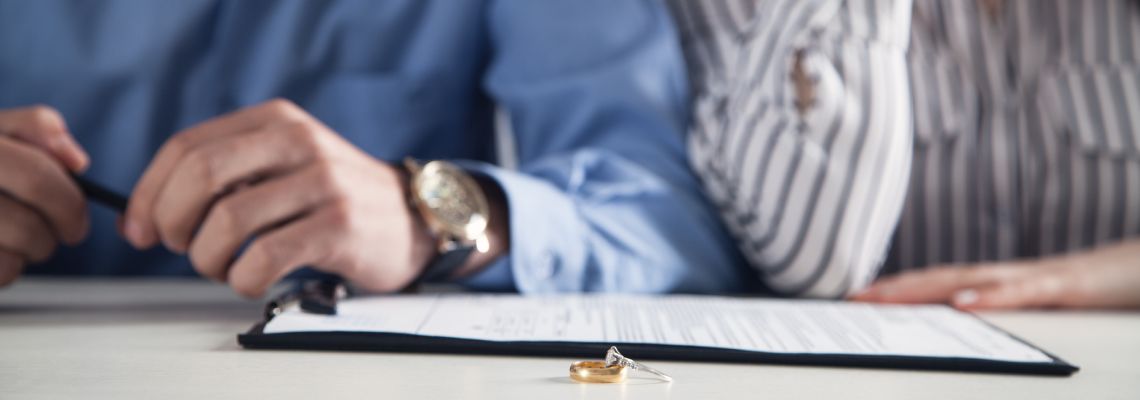Couple with divorce contract and ring on desk.