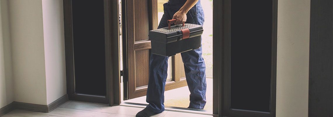 Repairer coming in the house with toolbox in his hand