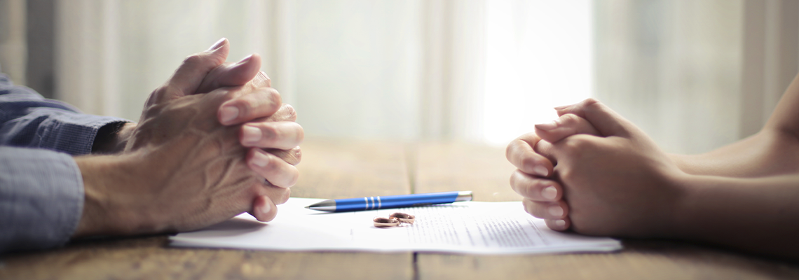 Divorce papers and ring between couple on a table