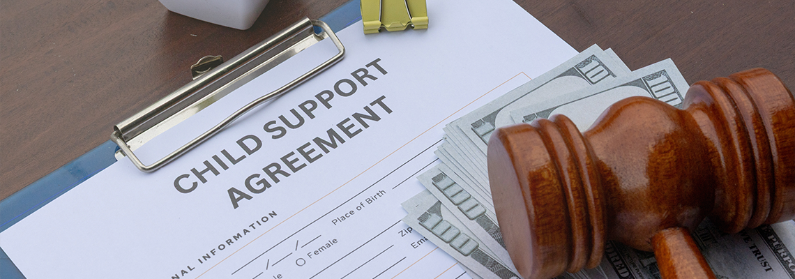 Child support agreement paper on a desk with cash, a gavel, and a calculator