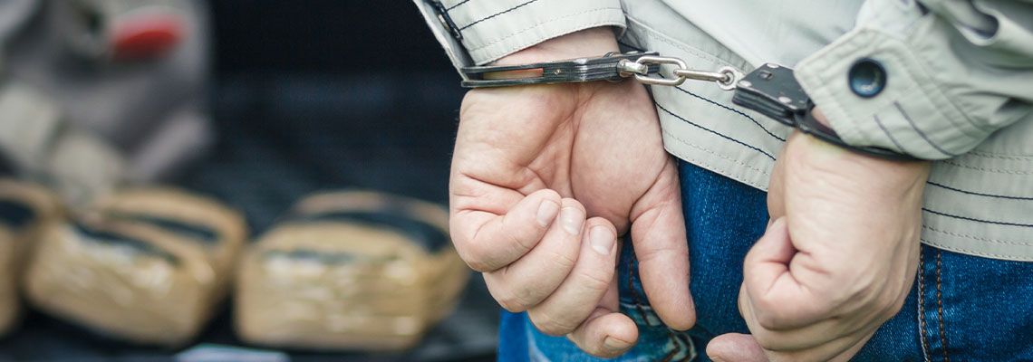 Handcuffed man with seized drugs