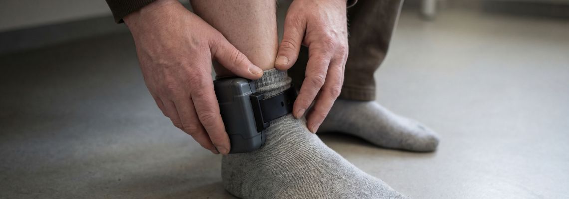 Man with ankle monitor device
