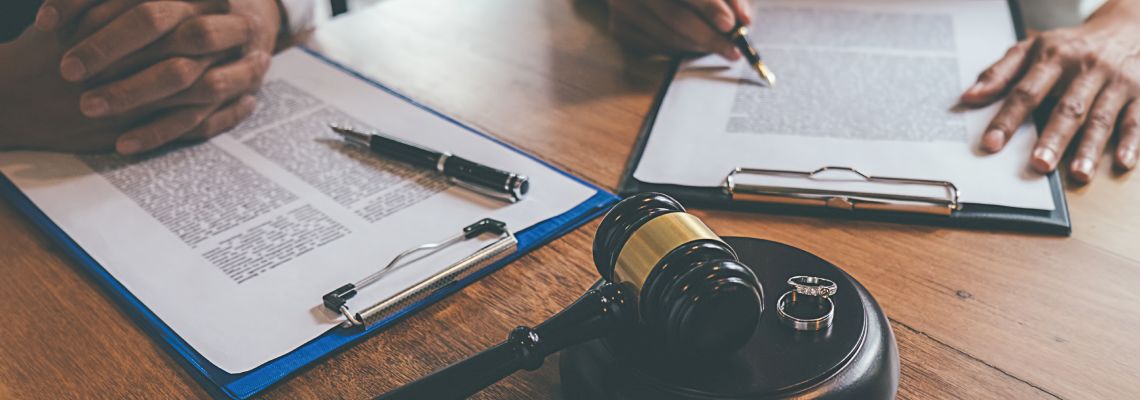 Gavel with wedding rings and couples signing divorce papers