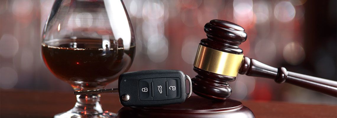Alcohol, car keys and gavel on wooden table