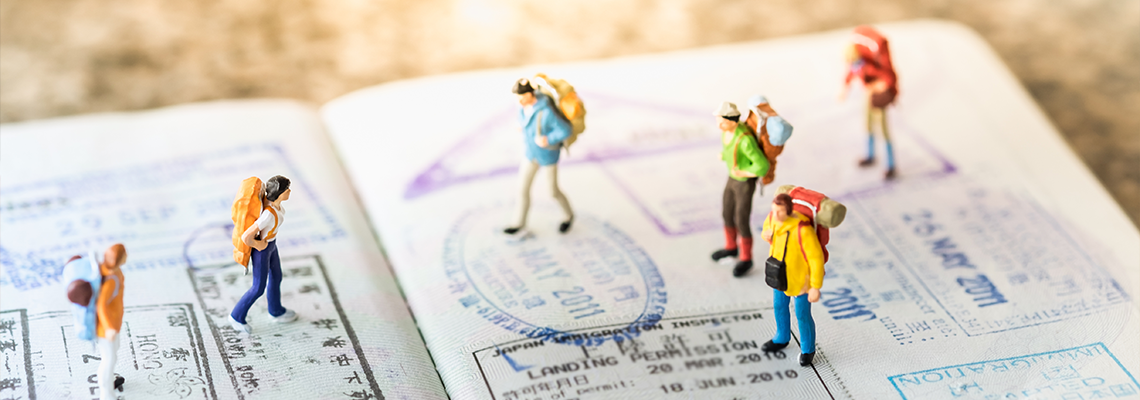 Group of miniature with backpack walking and standing on passport with immigration stamps