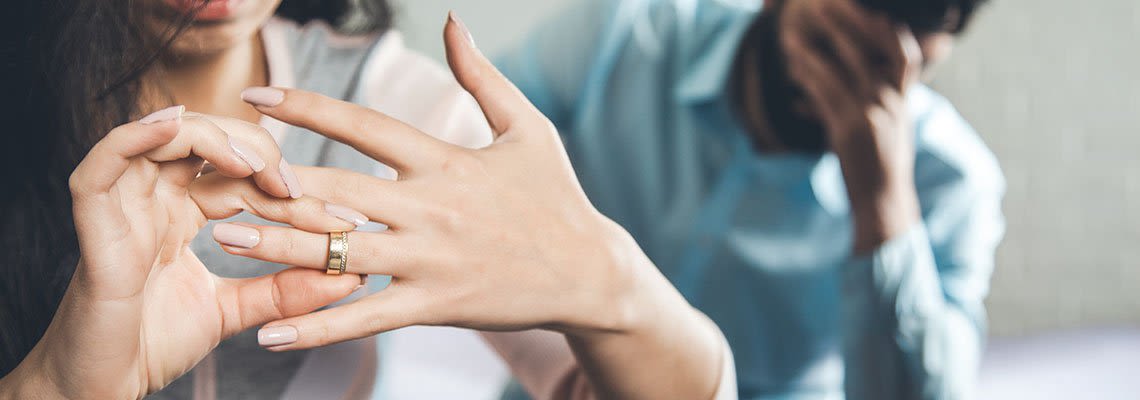 Woman removing a ring with an upset man behind her