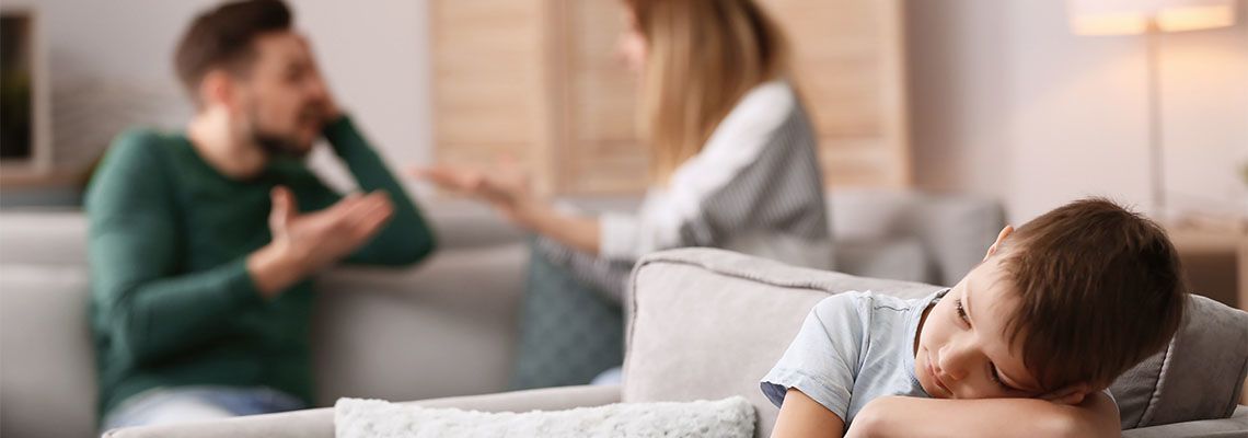 boy sitting in armchair while parents arguing at home