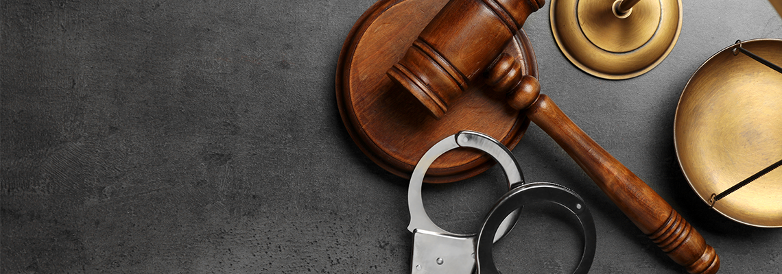 Judge's gavel, handcuffs and scales on grey background