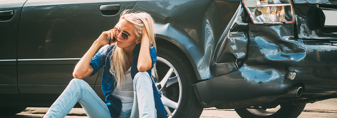 Girl sits on the road, near the broken car and calls on the phone, calling for help