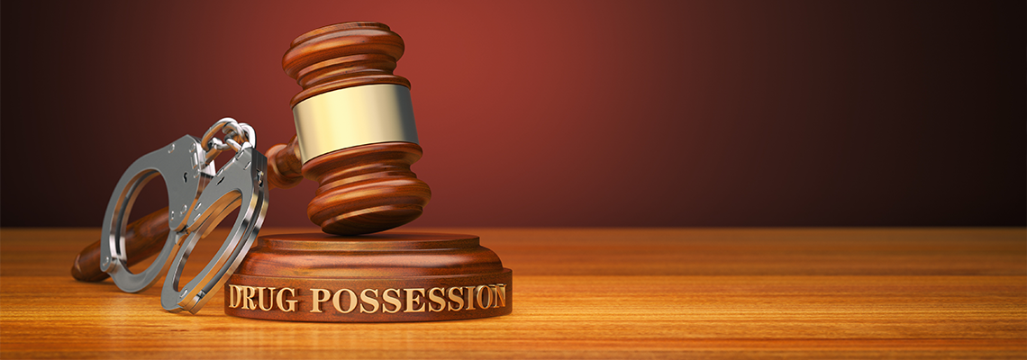 Drug Possession and gavel with handcuff on table