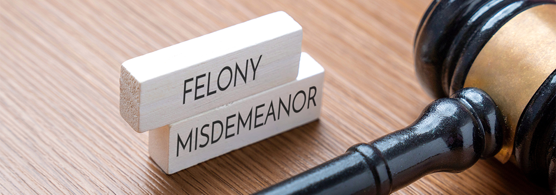 A judge’s gavel next to wooden blocks labeled Felony and Misdemeanor