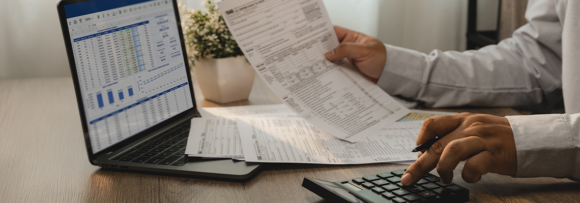 Accountant reviewing financial report and tax documents on laptop