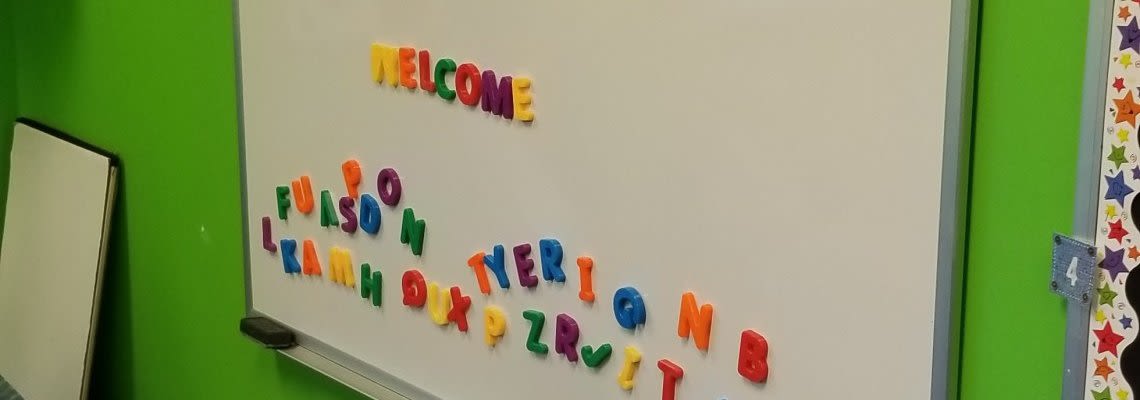White board in classroom that says "WELCOME" in block letters