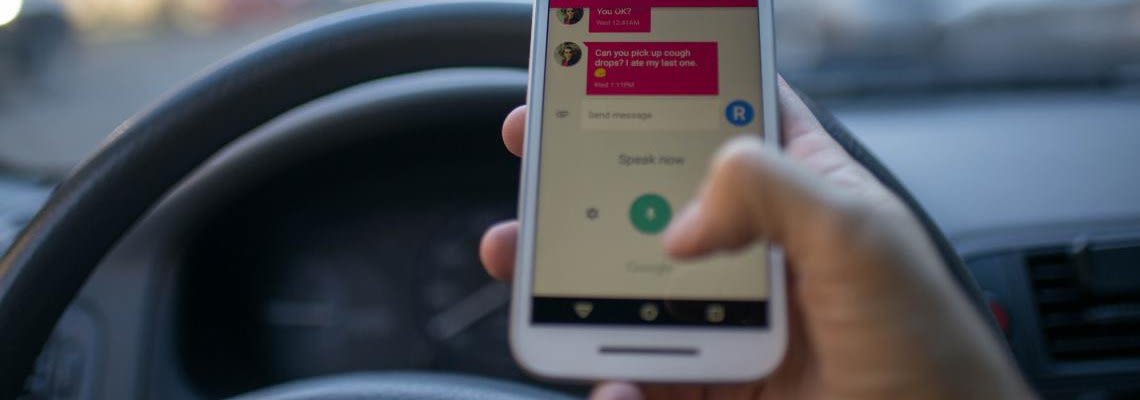 Close up of hand holding a phone and texting while driving