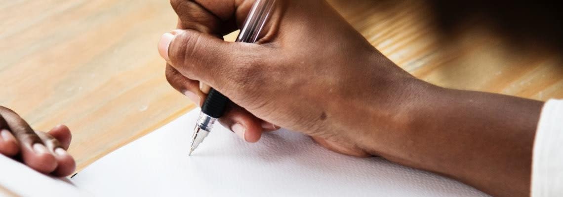 Hand writing something in notebook with pen