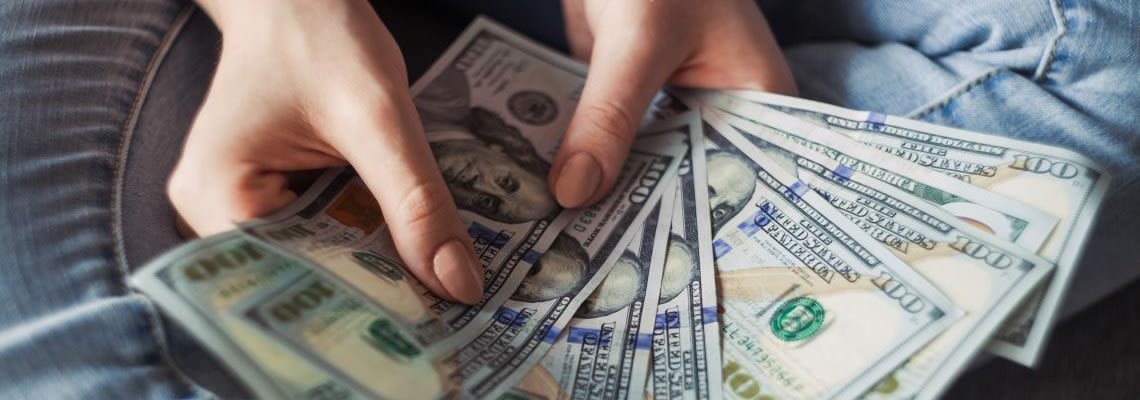 Person holding multiple one-hundred dollar bills