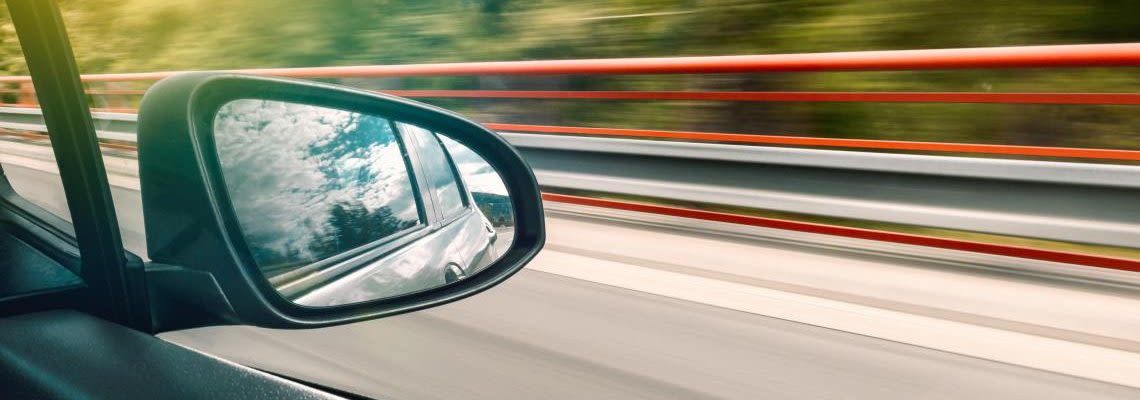 Close up of a rear-view mirror in car while driving fast