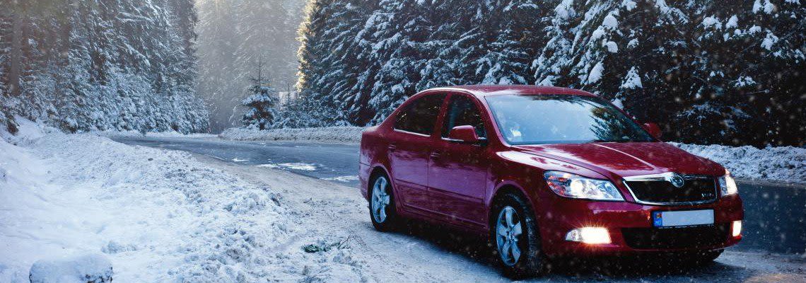 Red car on the road in the winter with snow
