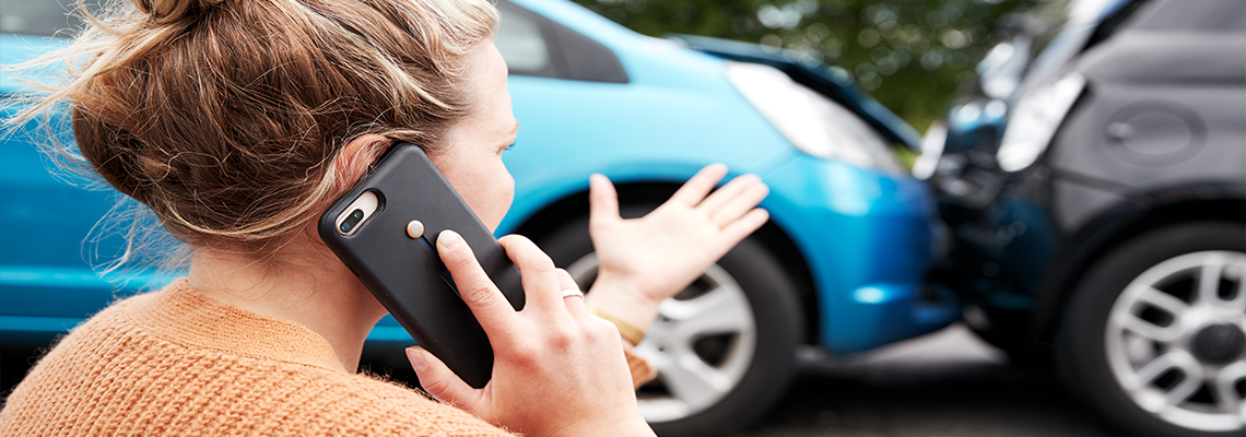 Person looking at car accident with phone up to ear