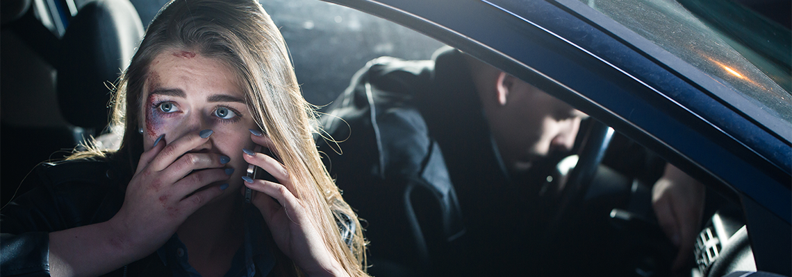 Person in passenger seat of car looking fearful on the phone