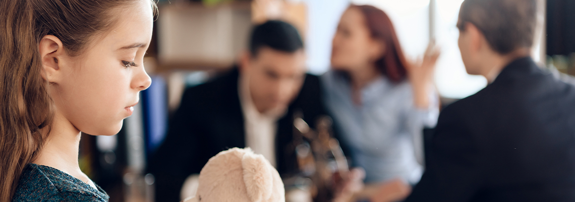 Upset girl with a bear in hand is standing and sad