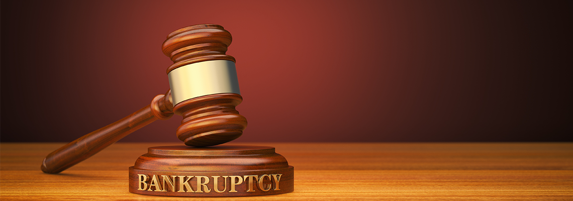 Wooden gavel on desk with label reading bankruptcy