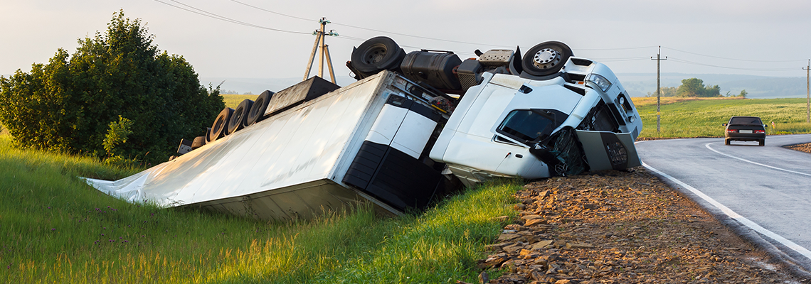 Semi-truck upside down next to country road
