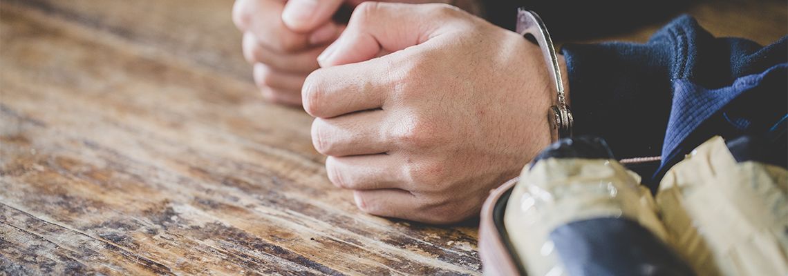 Handcuffed man besides pouch of drugs