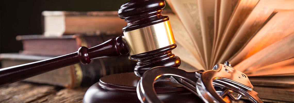 Wooden gavel and books on wooden table with handcuff