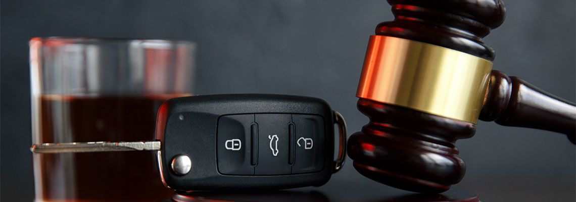 Gavel, car keys and glass of alcohol on table