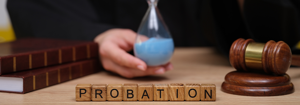 A judge holds an hourglass filled with blue sand, symbolizing time in a courtroom