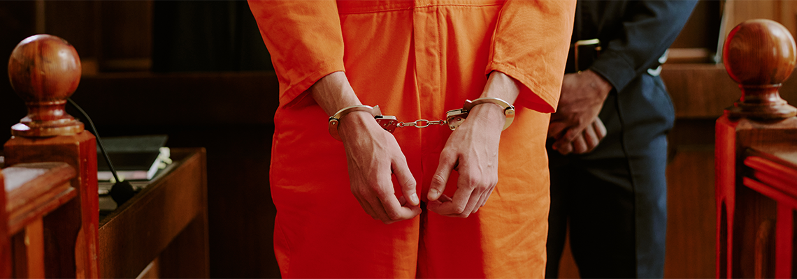 Adult man standing in courtroom wearing handcuffs with hands in front
